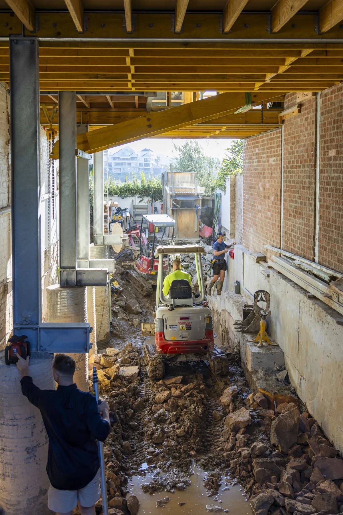 House propped on steel beams while the crew excavates and underpins beneath it