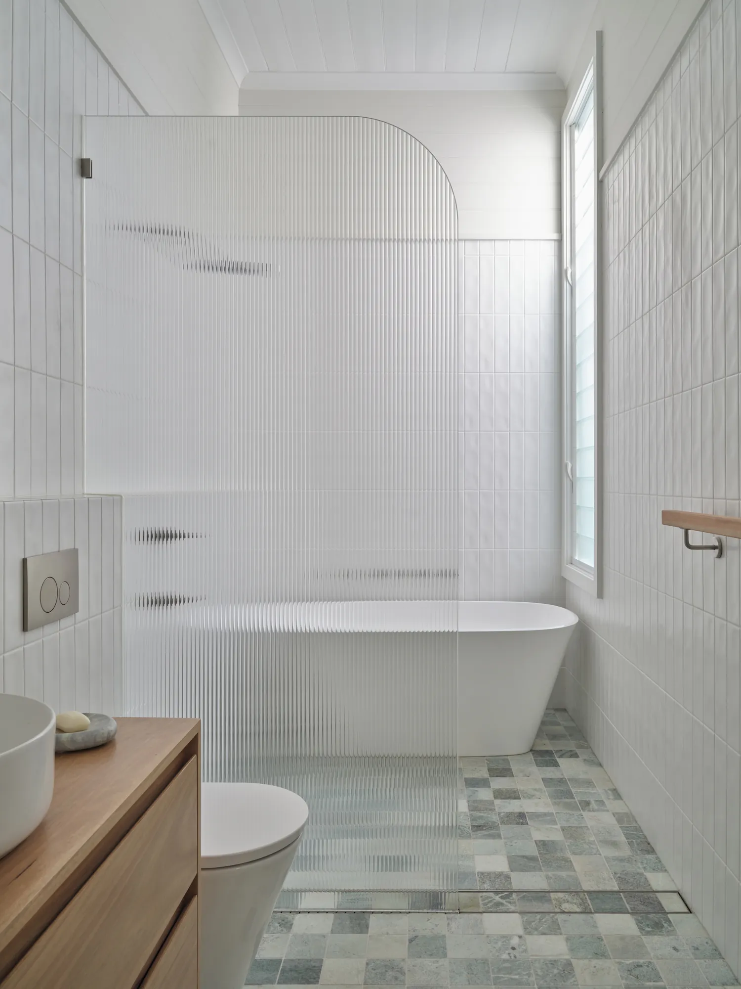 Bathroom with freestanding bath and fluted screen.