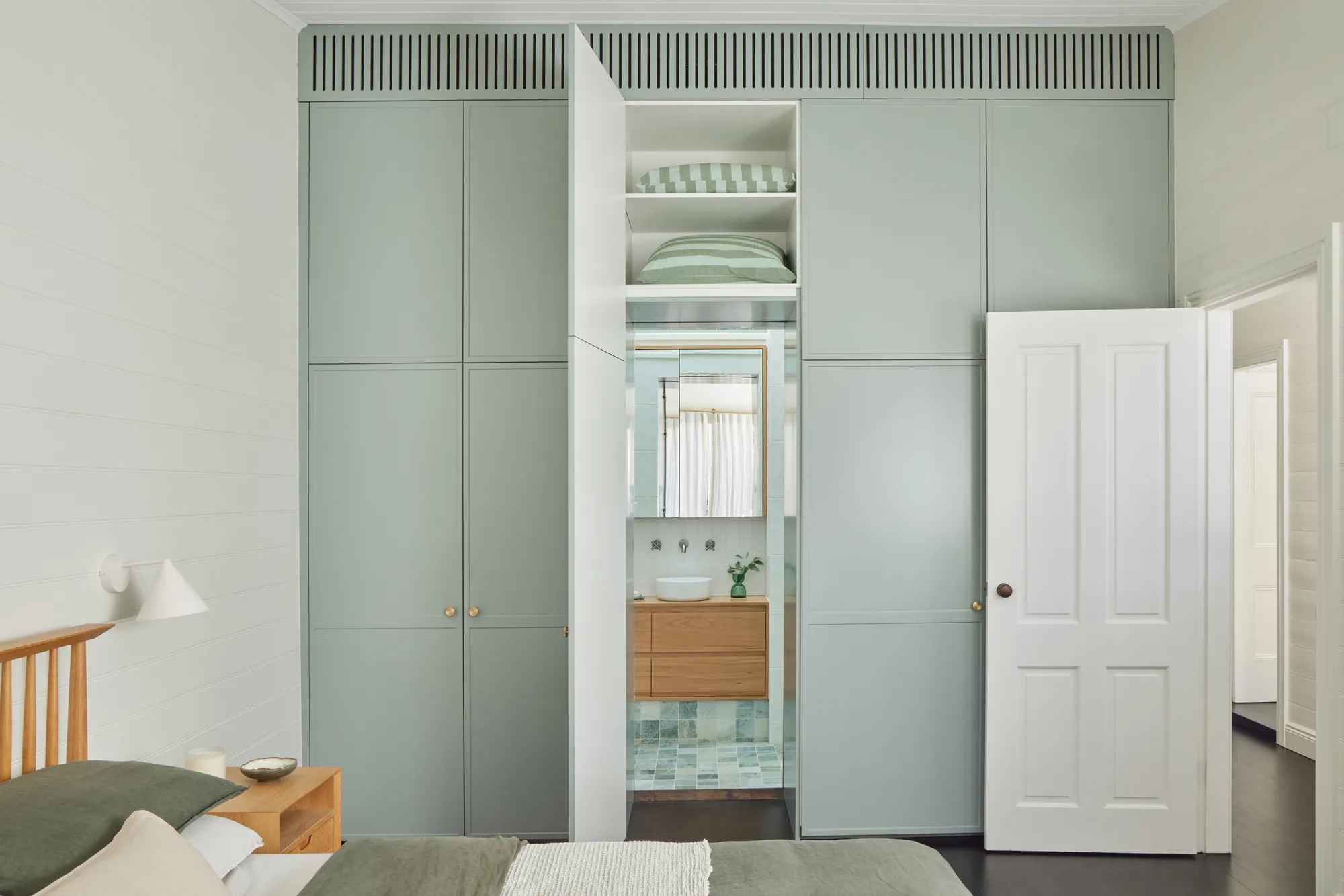Sage wardrobe wall with a hidden door to the ensuite.