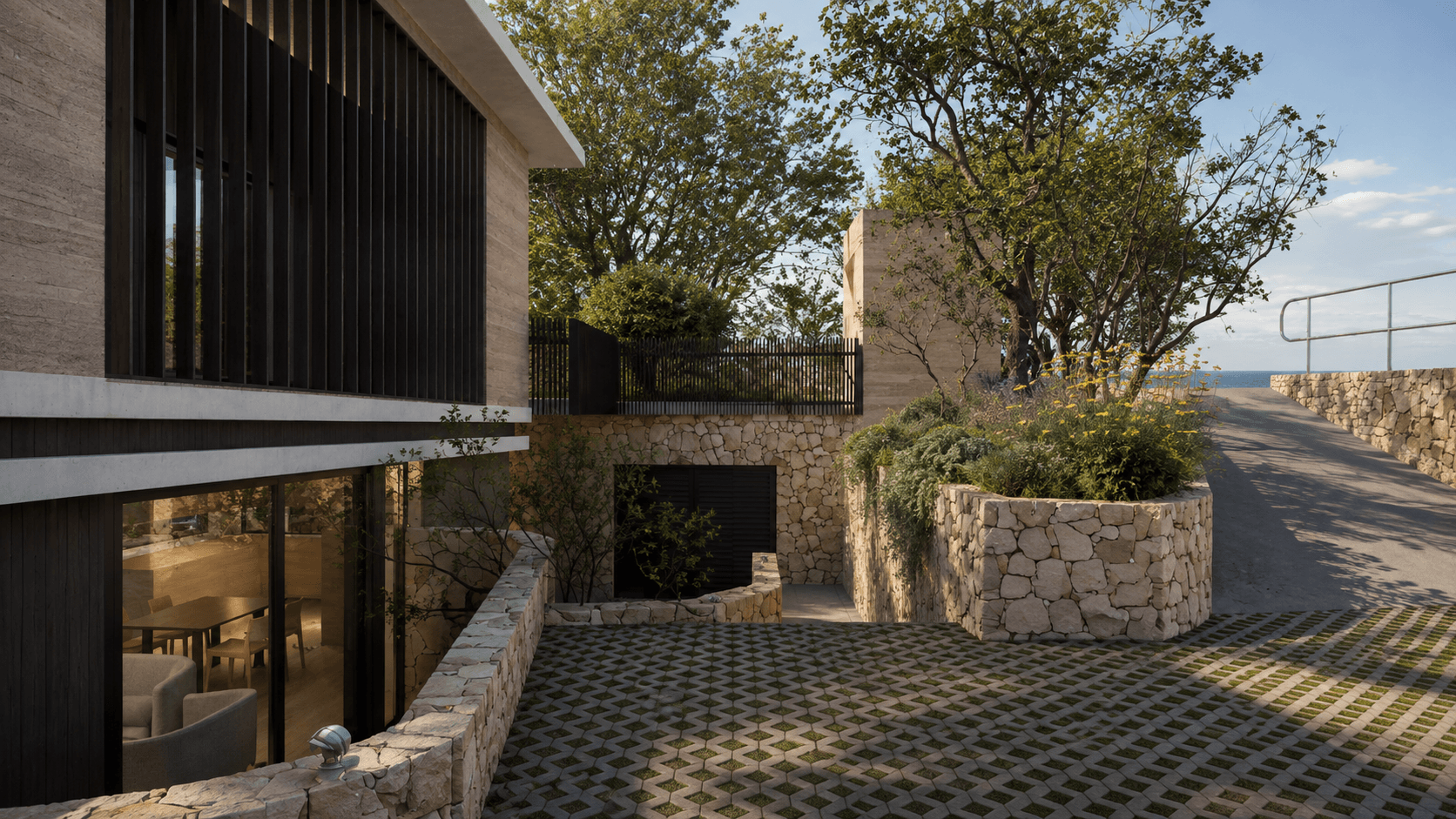 Landscaped courtyard between contemporary building forms, featuring dark timber cladding, stone walls, native planting and framed views toward the coast.